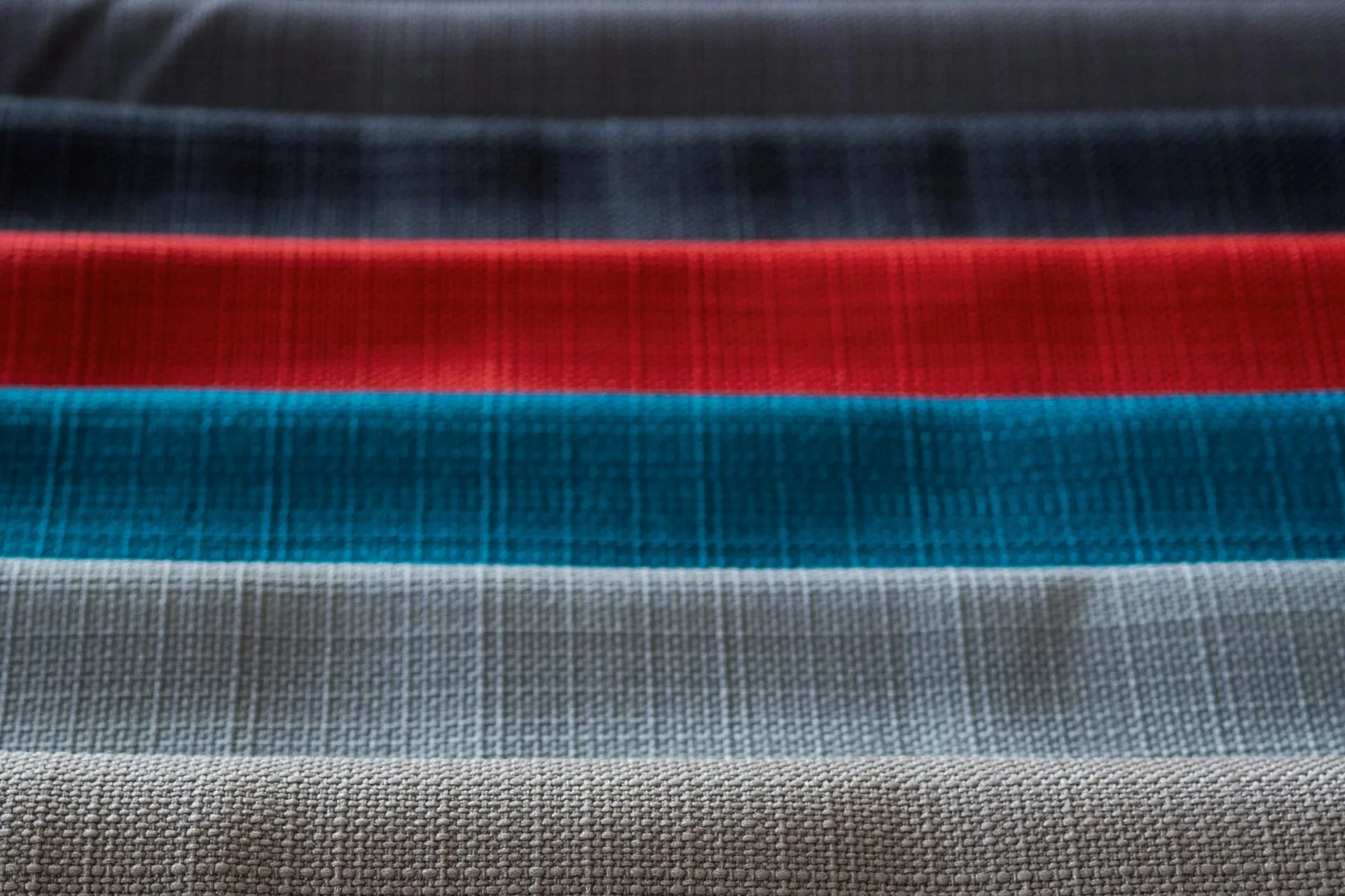 Zestaw próbek materiałów na rolety okienne w różnych kolorach: czerwonym, niebieskim, szarym i beżowym